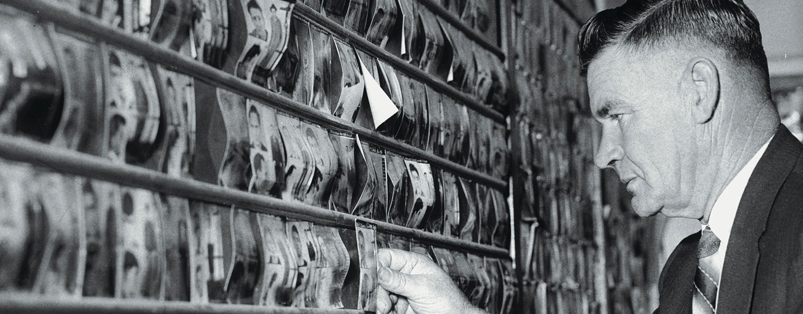 Research Photo of a detective looking at a wall of mug shots